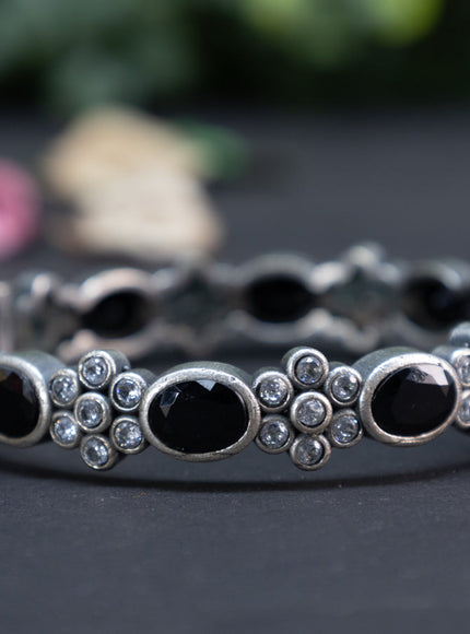 Oxidised floral design screw type bangle with black and cz stones