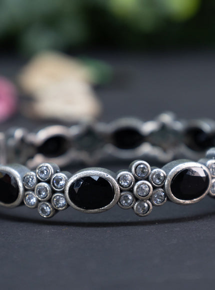 Oxidised floral design screw type bangle with black and cz stones