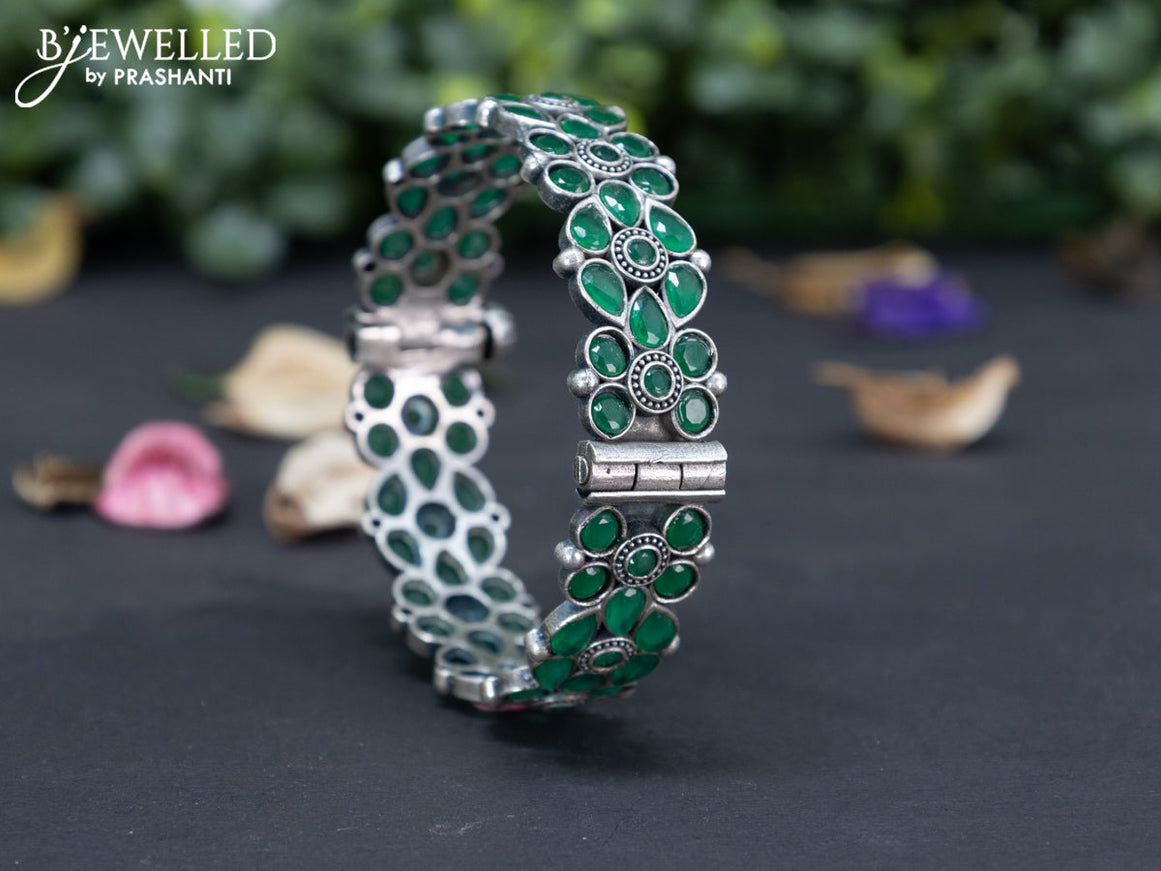 Oxidised floral design screw type bangle with emerald stones